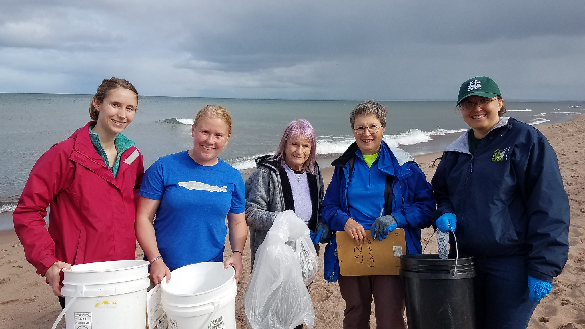 Five women at Adopt-a-beach holding trash and buckets