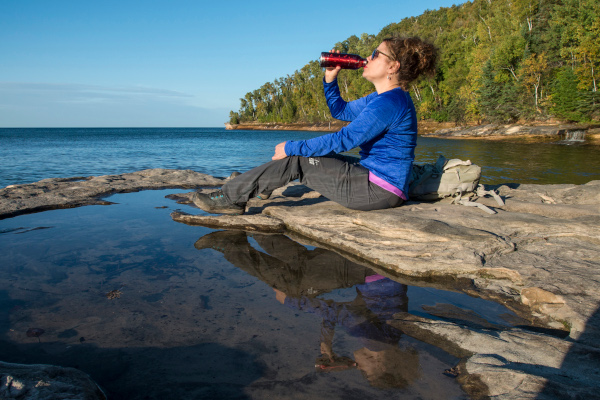 Women drinking from a water bottle on a Lake Superior shore, photo by Lloyd DeGrane