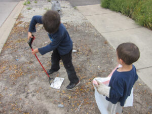 Two boys clean up trash in their neighborhood
