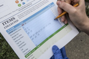 A hand recording litter counts on a form.