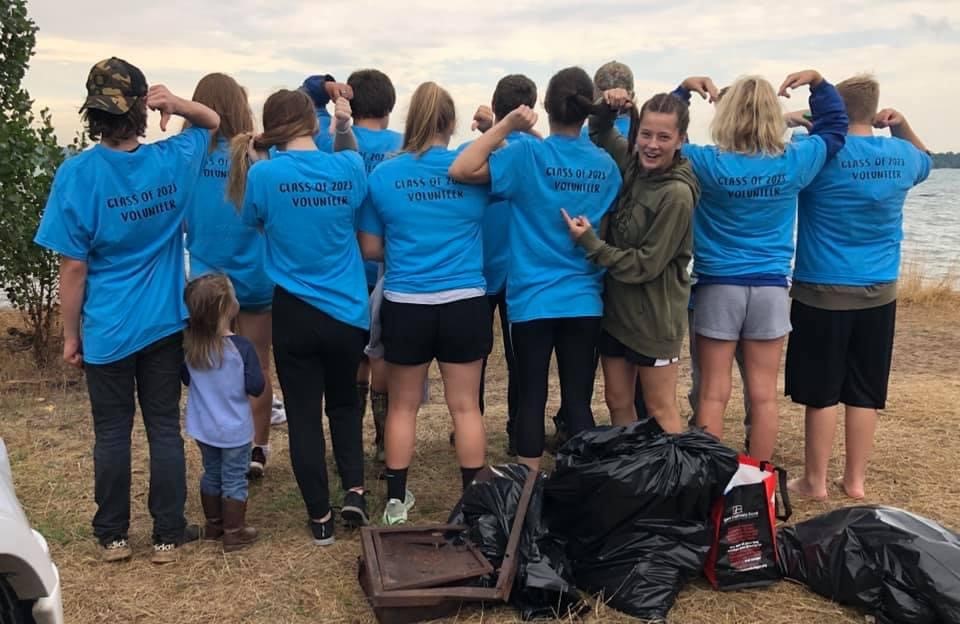 A group of volunteers in matching t-shirts faces Lake Michigan.