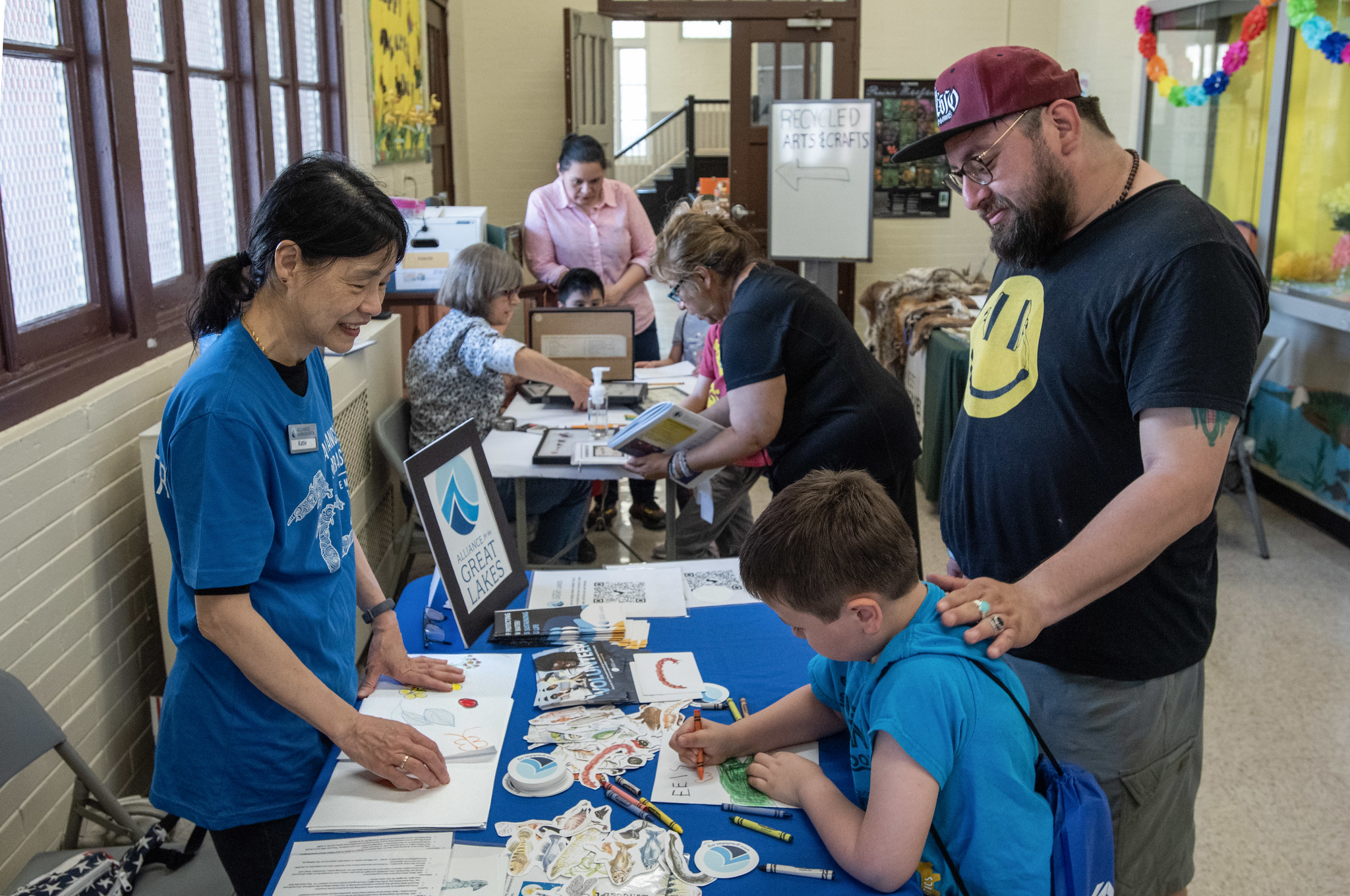 A woman interacts a father and son a table covered with activities.