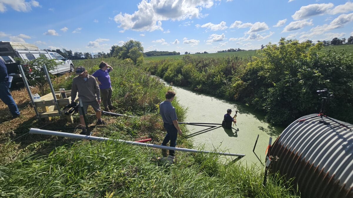 A worker wades into the water to install equipment.