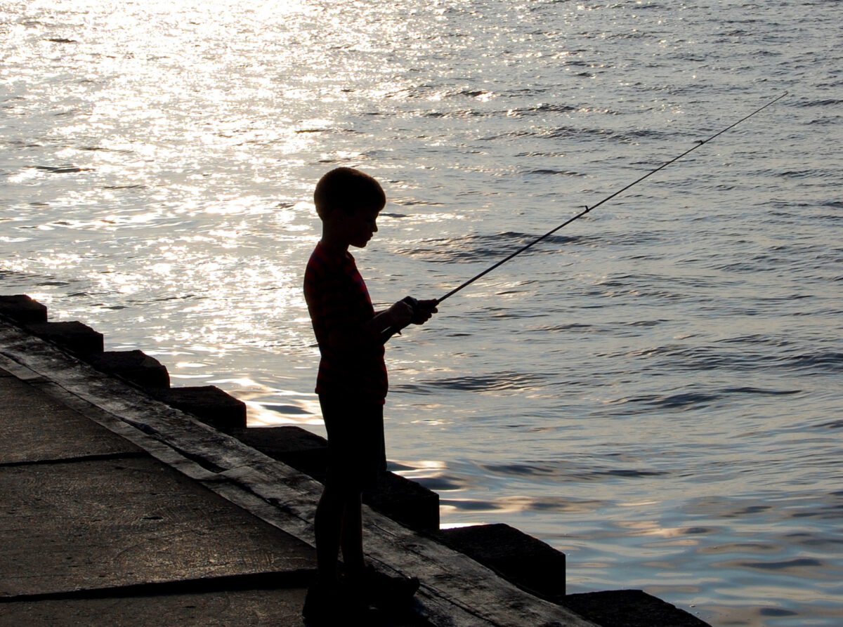A boy fishes from a pier.