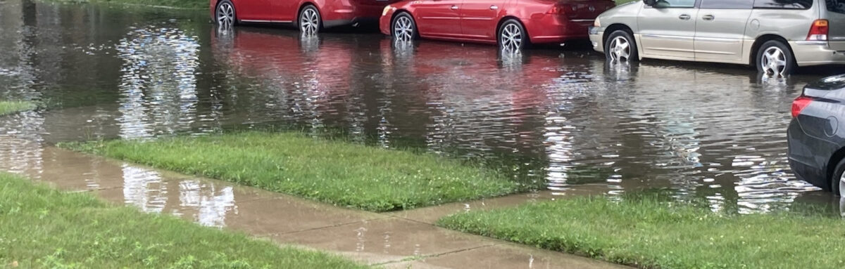 Cars parked on a flooded street with water up to the hubcaps.